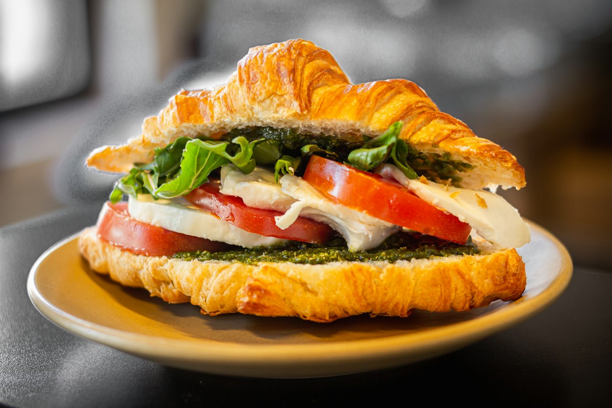 Croissant sandwich with tomato, mozzarella and greens